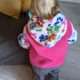 back view of a little girl wearing a pink and paw print hoodie
